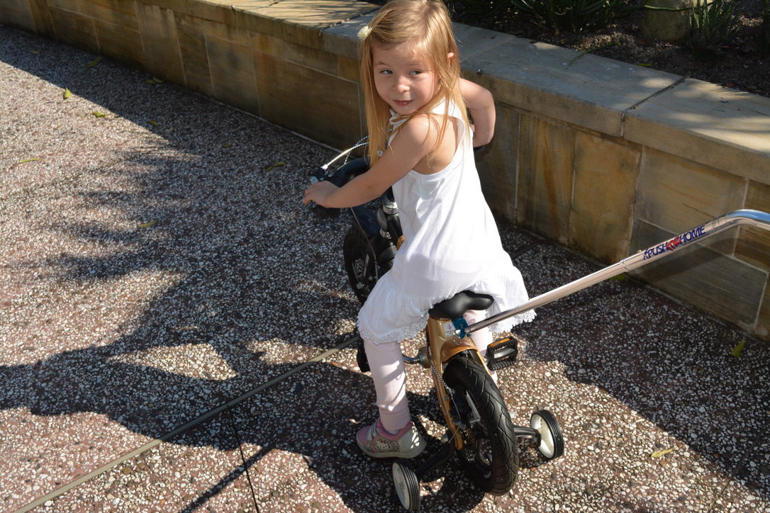 Parent using a bike handle to help a child learn steering and balance on their first bike